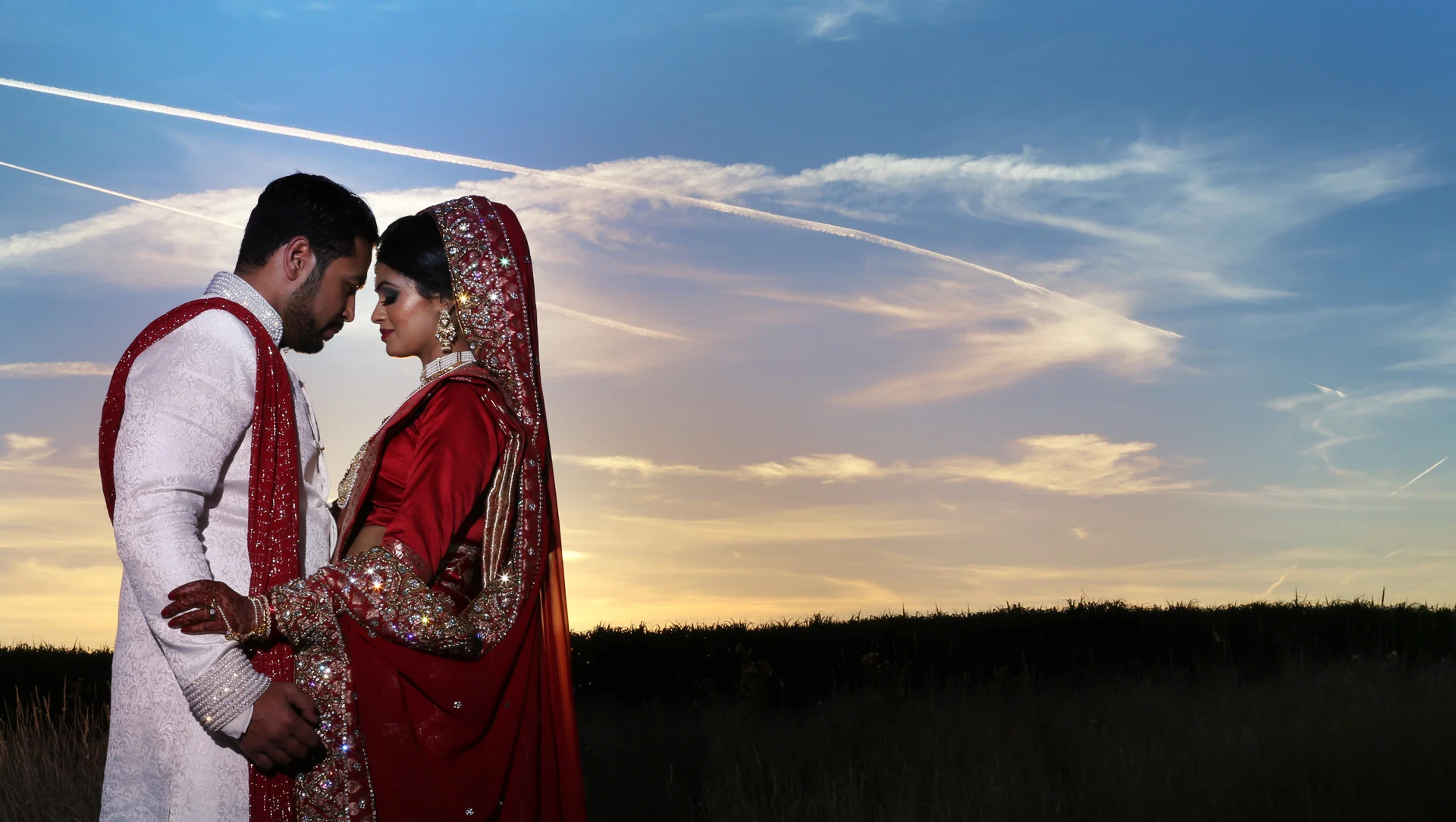 Bride and groom in traditional Asian wedding dress at sunset
