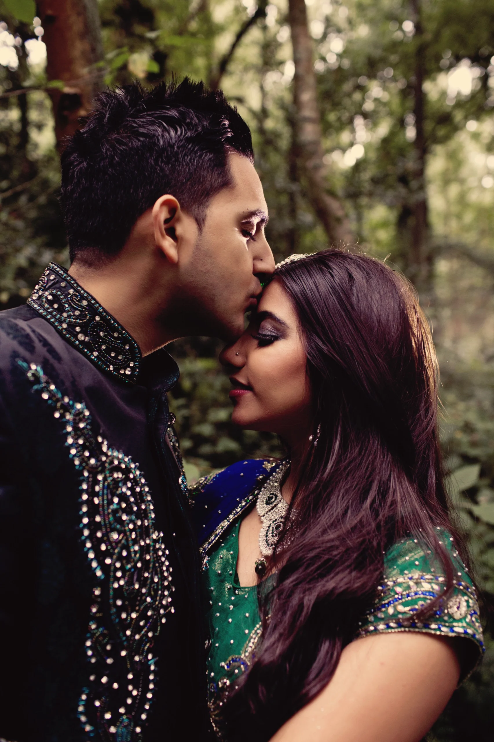 Groom kissing his bride's forehead in traditional Asian wedding dress