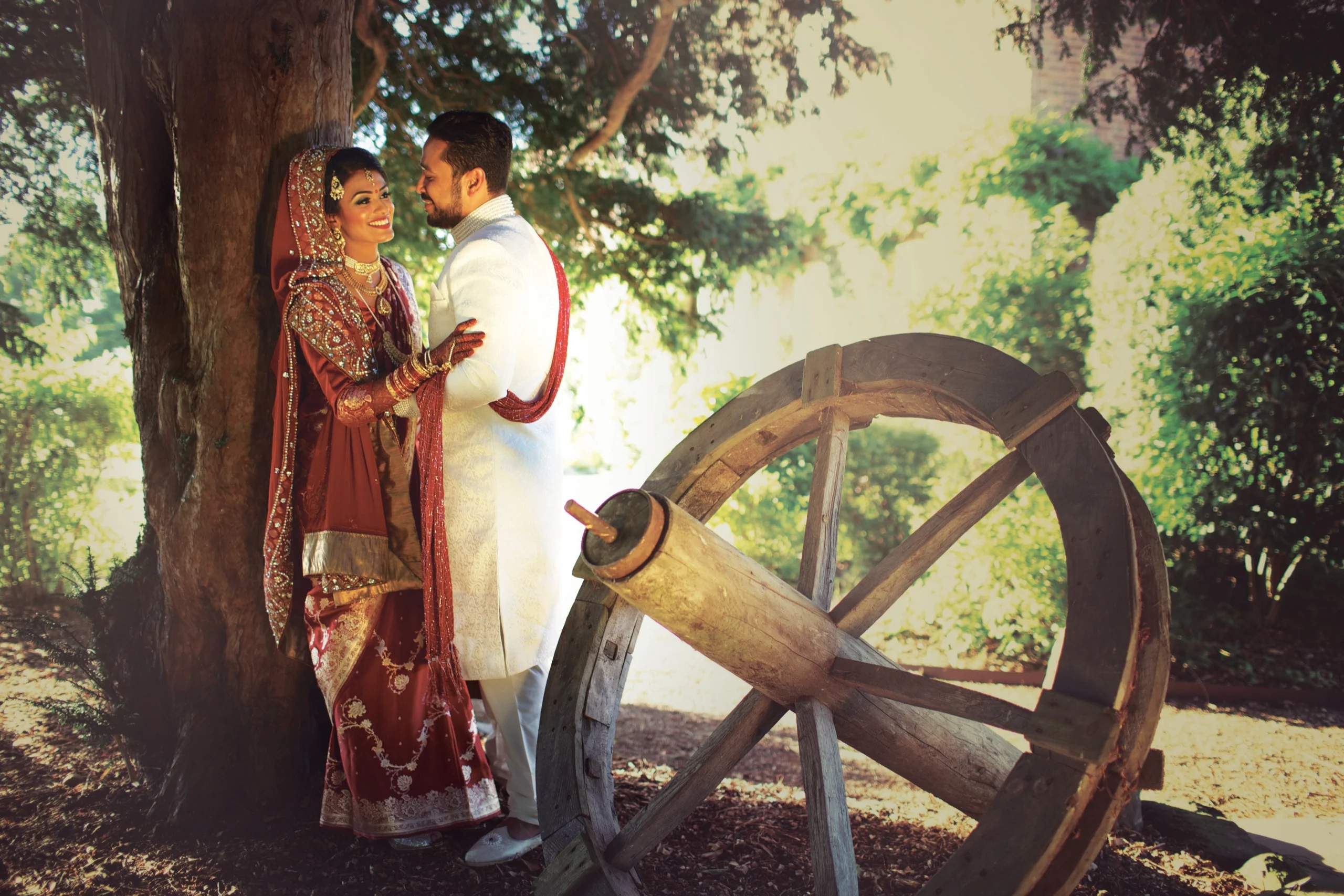 Bride and groom beside an old cart wheel in traditional dress