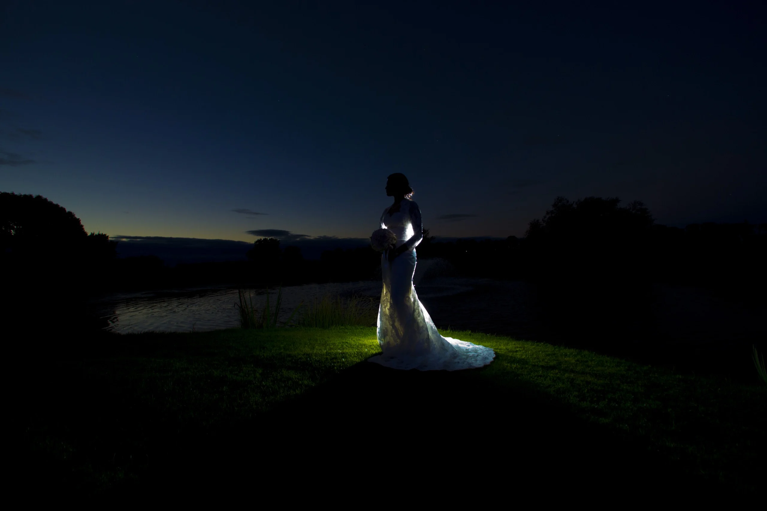 Bride standing alone at dusk under a deep blue winter sky