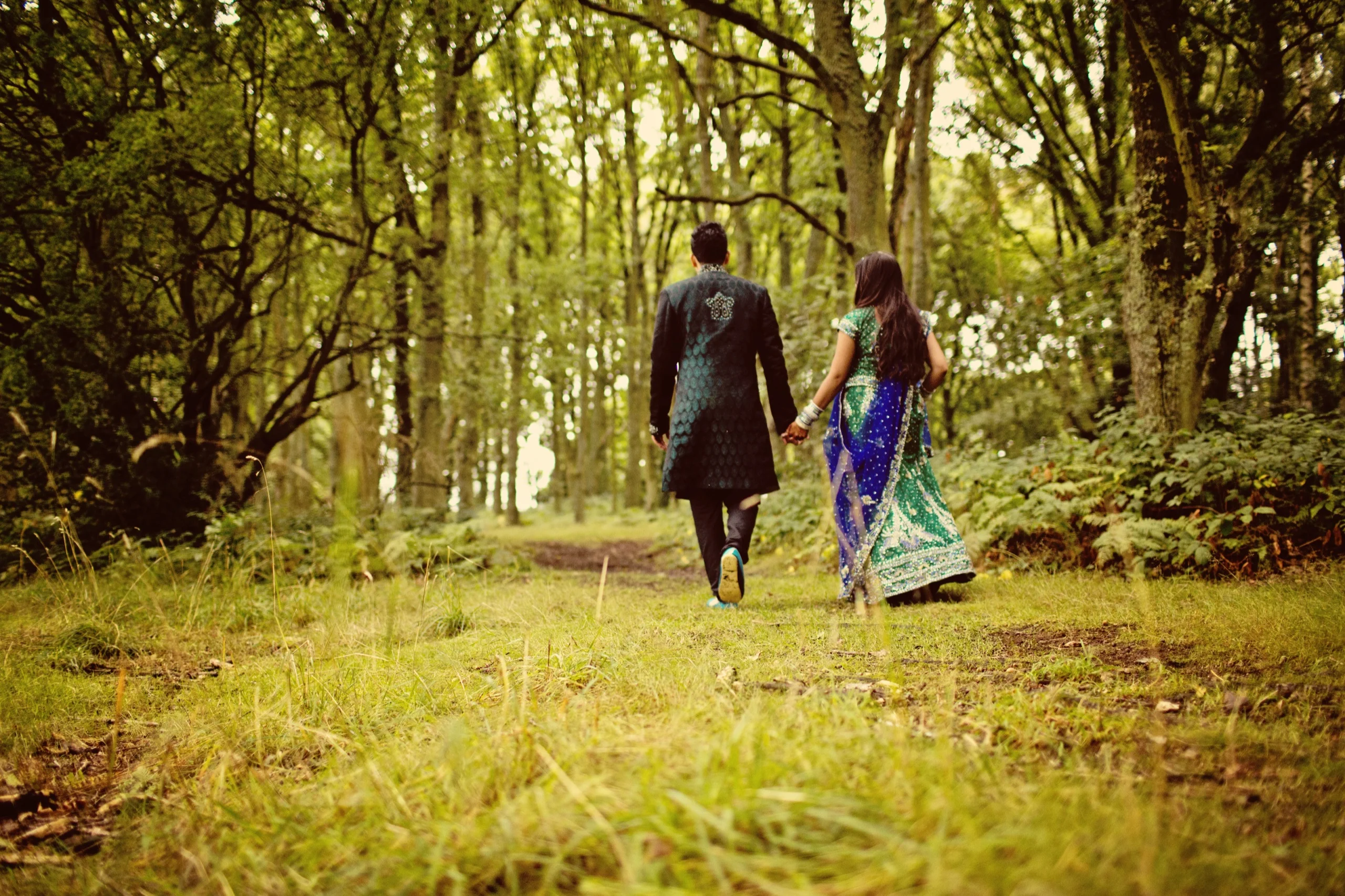 Couple walking hand in hand through a woodland